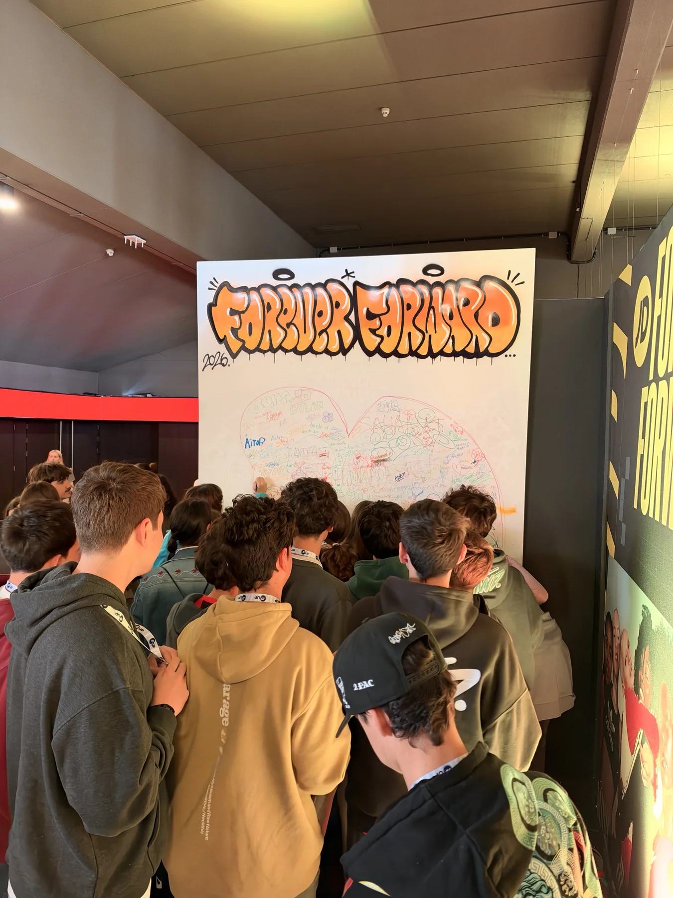 Grupo de alumnos de ESO esperando su turno para firmar el lienzo colaborativo «Forever Forward» de JD Sports en Kinépolis.