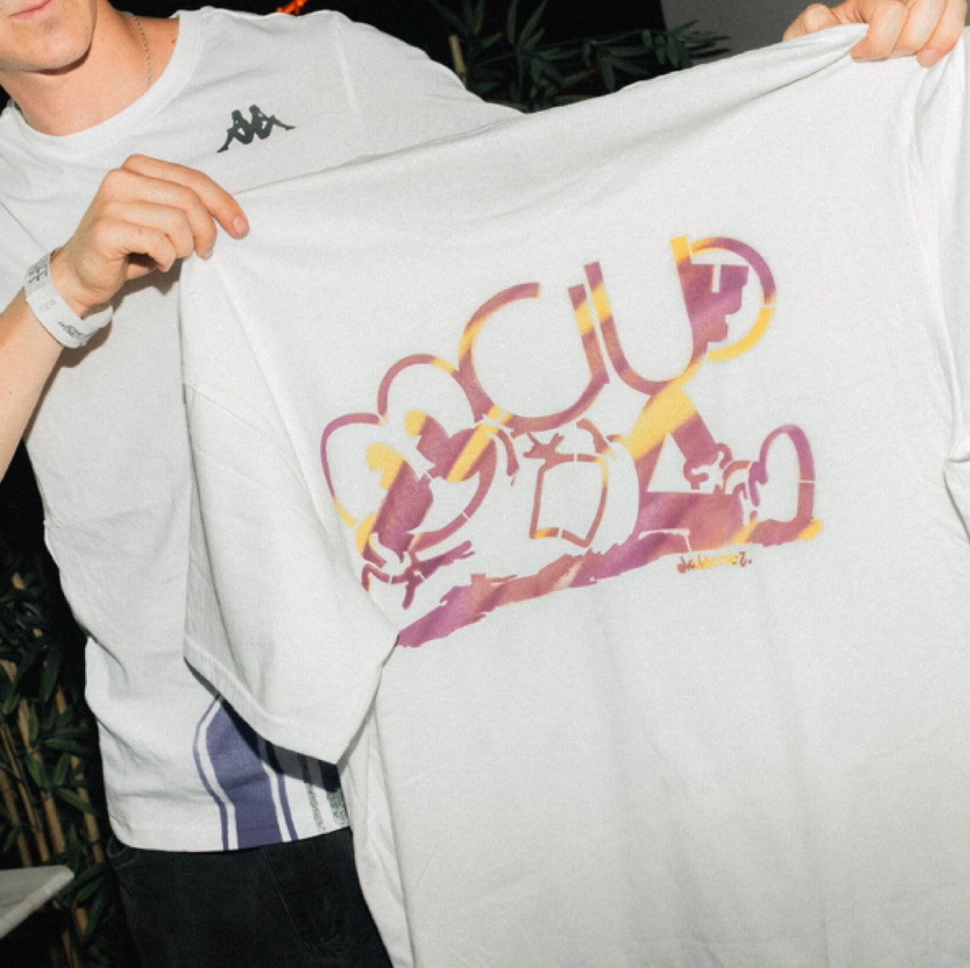 Asistentes a discoteca admirando camiseta exclusiva creada por artista de graffiti en Madrid durante una activación de marca nocturna para Fraeternity.