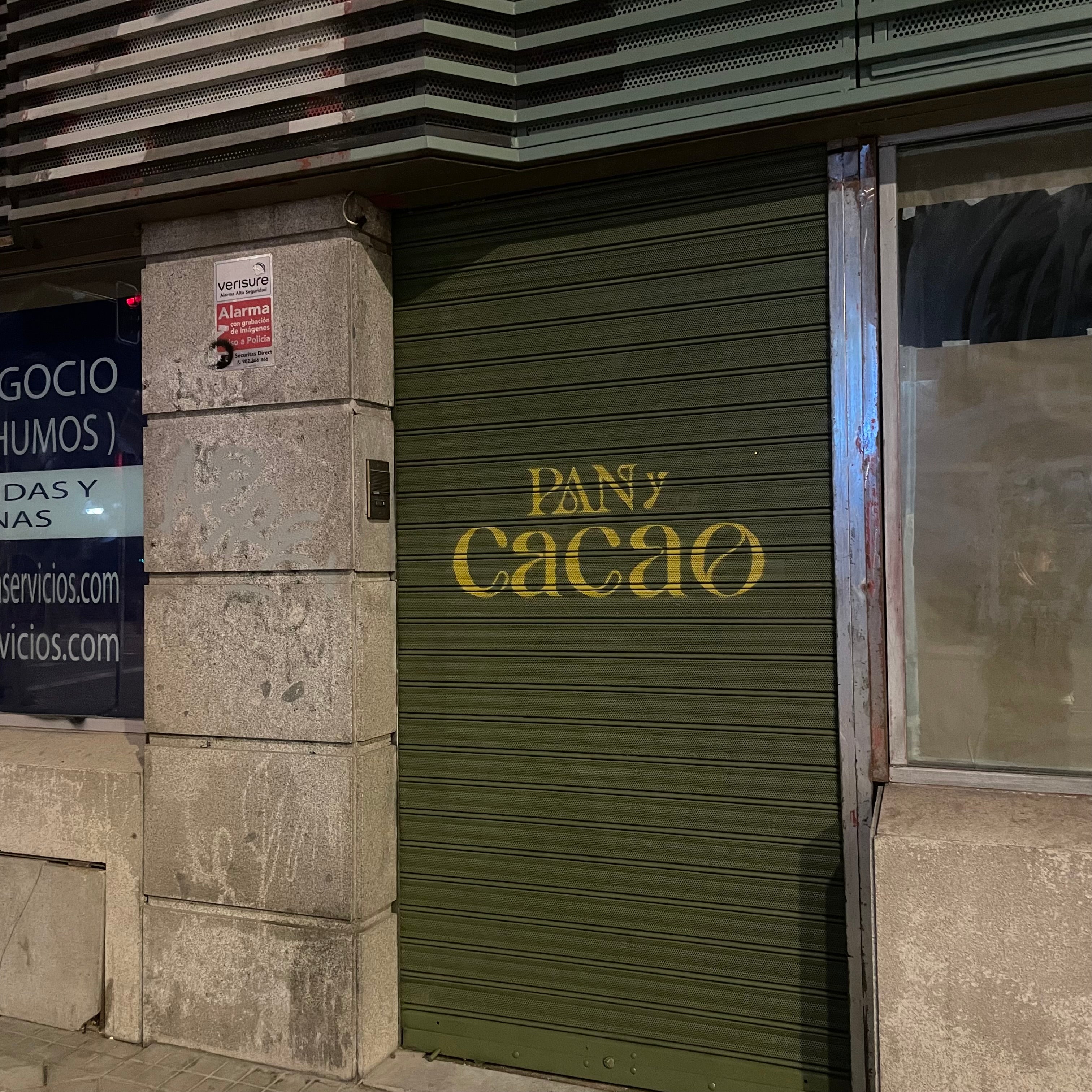 Fachada de local comercial en Madrid con cierre pintado en verde y dorado. Rotulación corporativa elegante para próxima apertura de panadería.