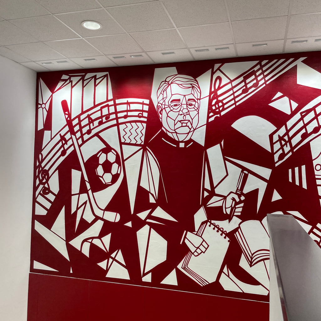 Detalle de retrato geométrico de D. Luis con pluma y libreta. Estilo artístico inspirado en Picasso pintado en pared de colegio.