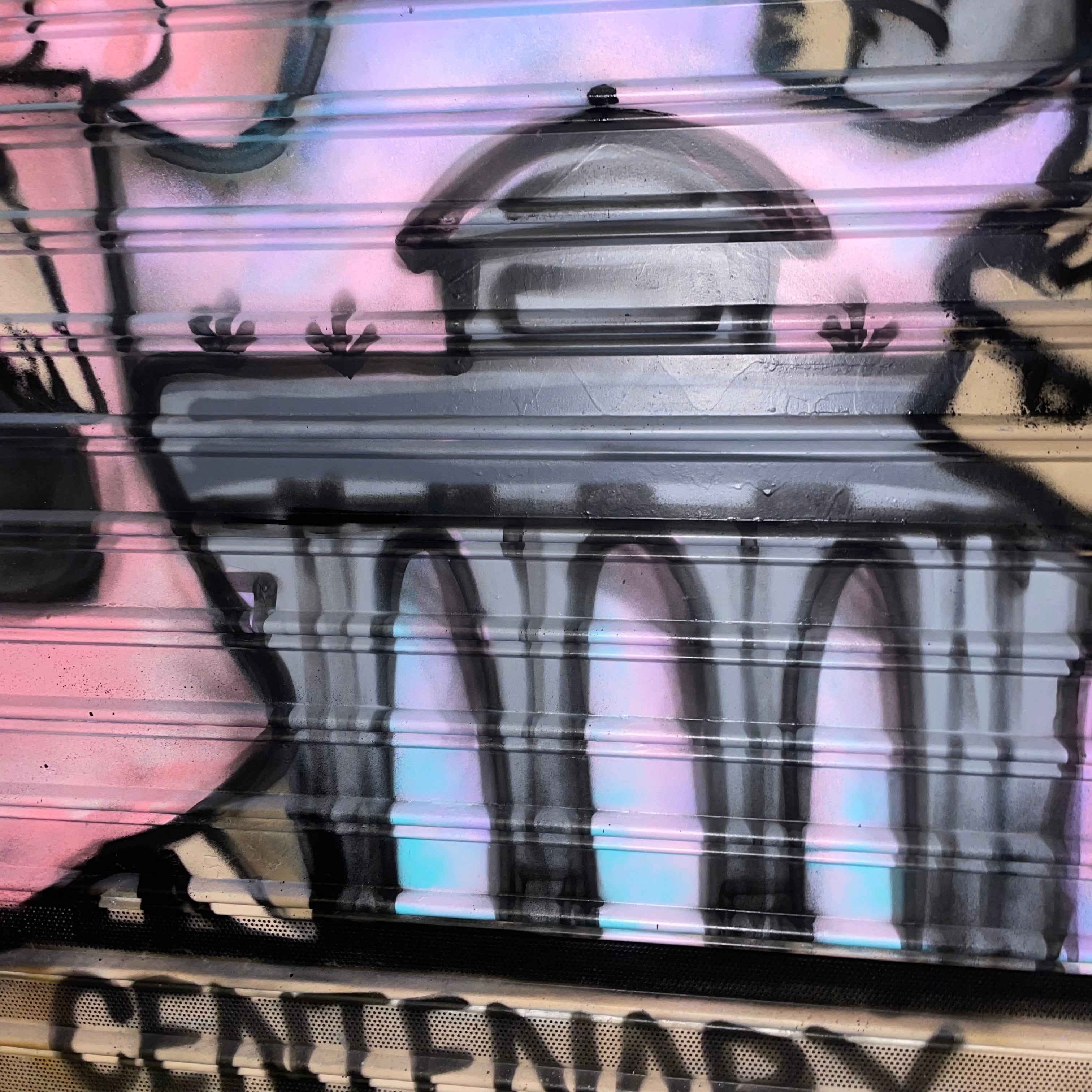 Detalle de pintura mural reinterpretando la placa del Ayuntamiento de Madrid para comercios centenarios. Figuras goyescas a color sobre cierre metálico.