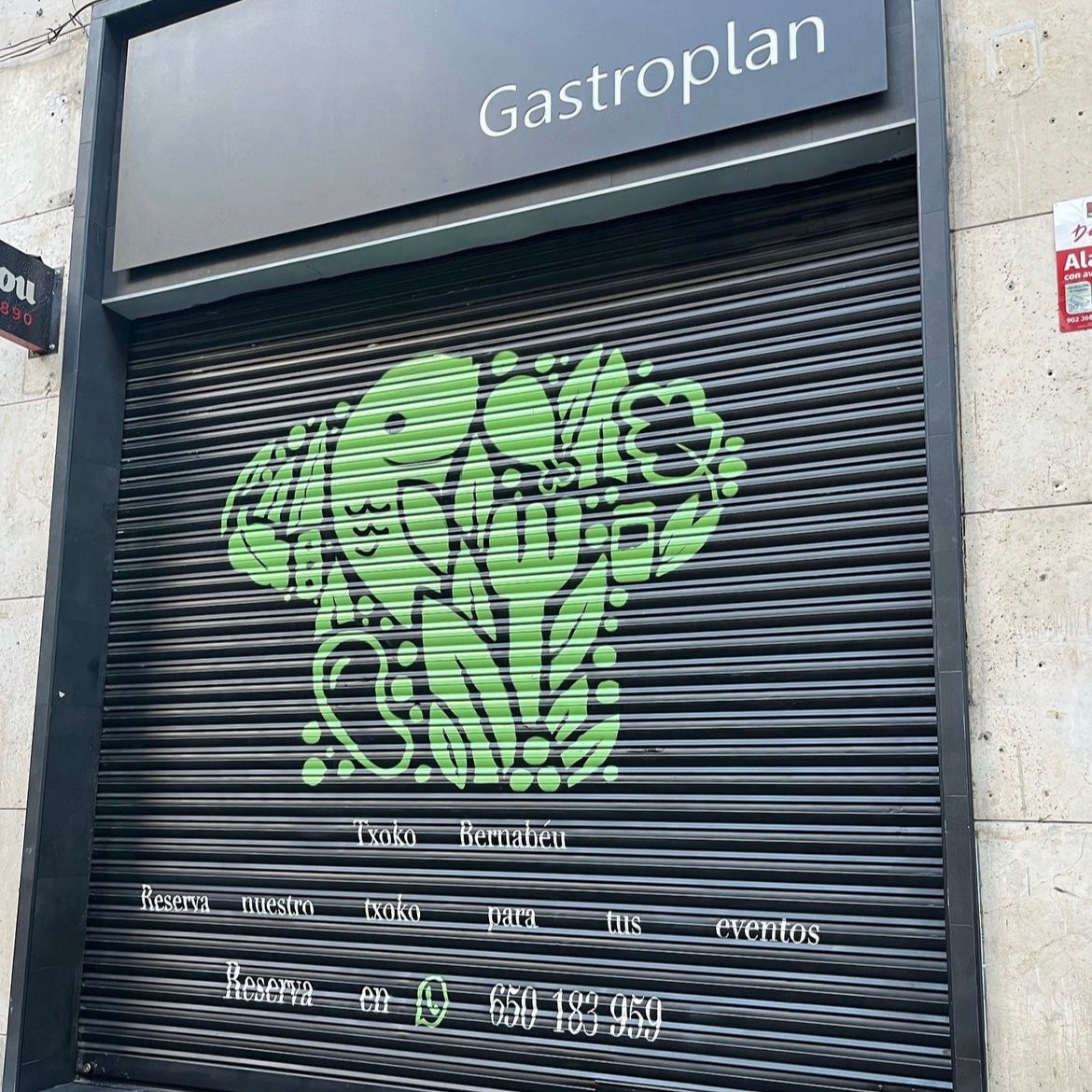 Cierre metálico negro de restaurante Gastroplan pintado con un gorro de chef verde formado por siluetas de pescado, cubiertos y vegetales. Incluye texto informativo y teléfono de reservas.