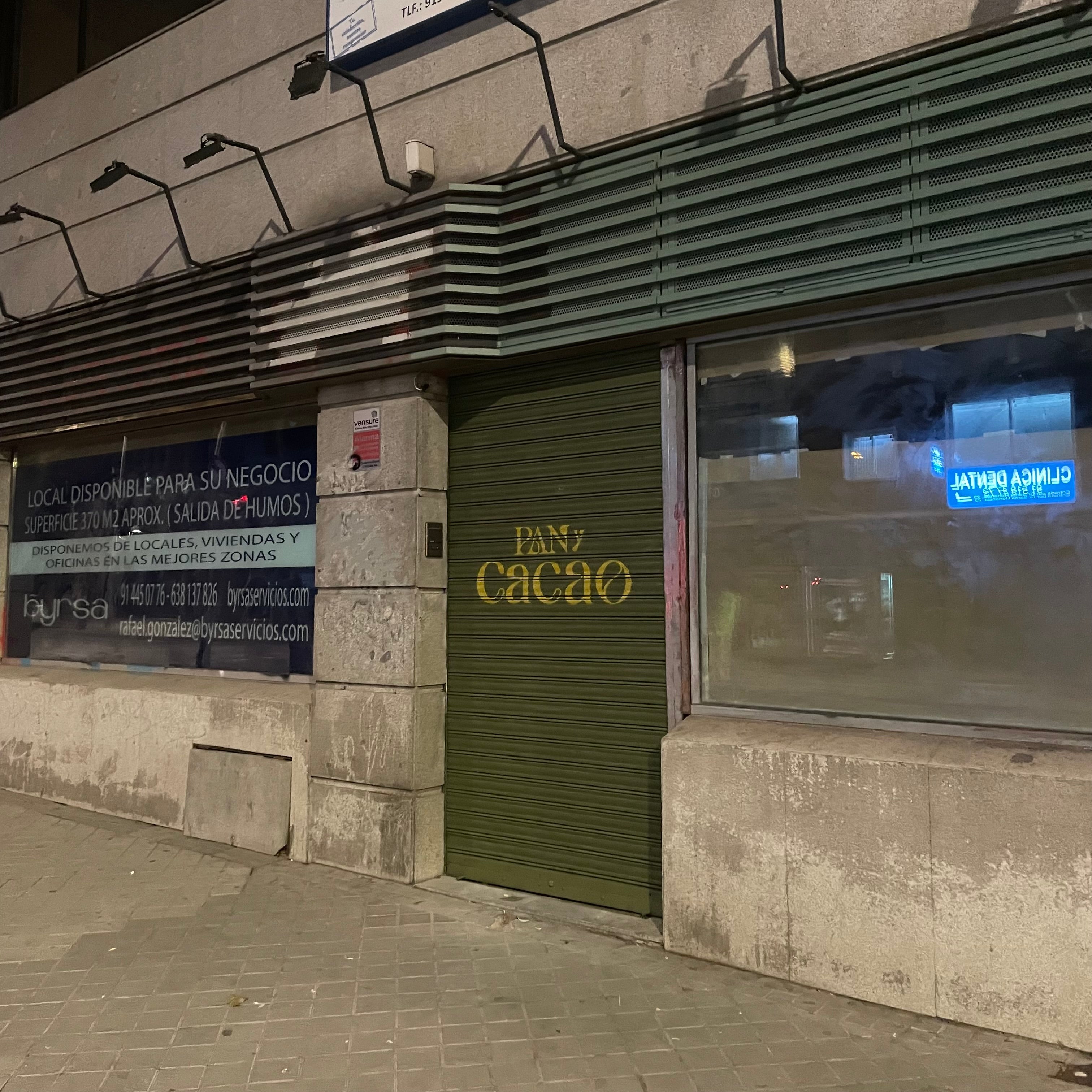 Fachada de local comercial en Madrid con cierre pintado en verde y dorado. Rotulación corporativa elegante para próxima apertura de panadería.