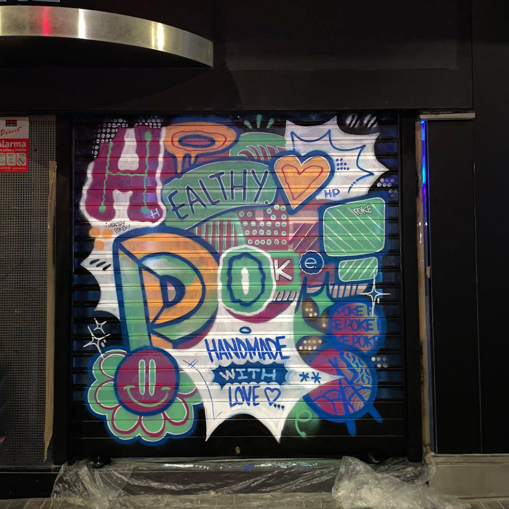 Cierre metálico de restaurante Healthy Poke pintado con graffiti colorido. Letras estilo burbuja, corazón y frase Handmade with Love sobre fondo negro.