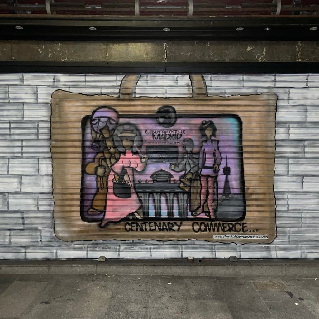 Cierre metálico de Jamonería Bartolomé pintado con mural artístico. Diseño de bolsa de compra con ilustración de placa de comercio centenario de Madrid.