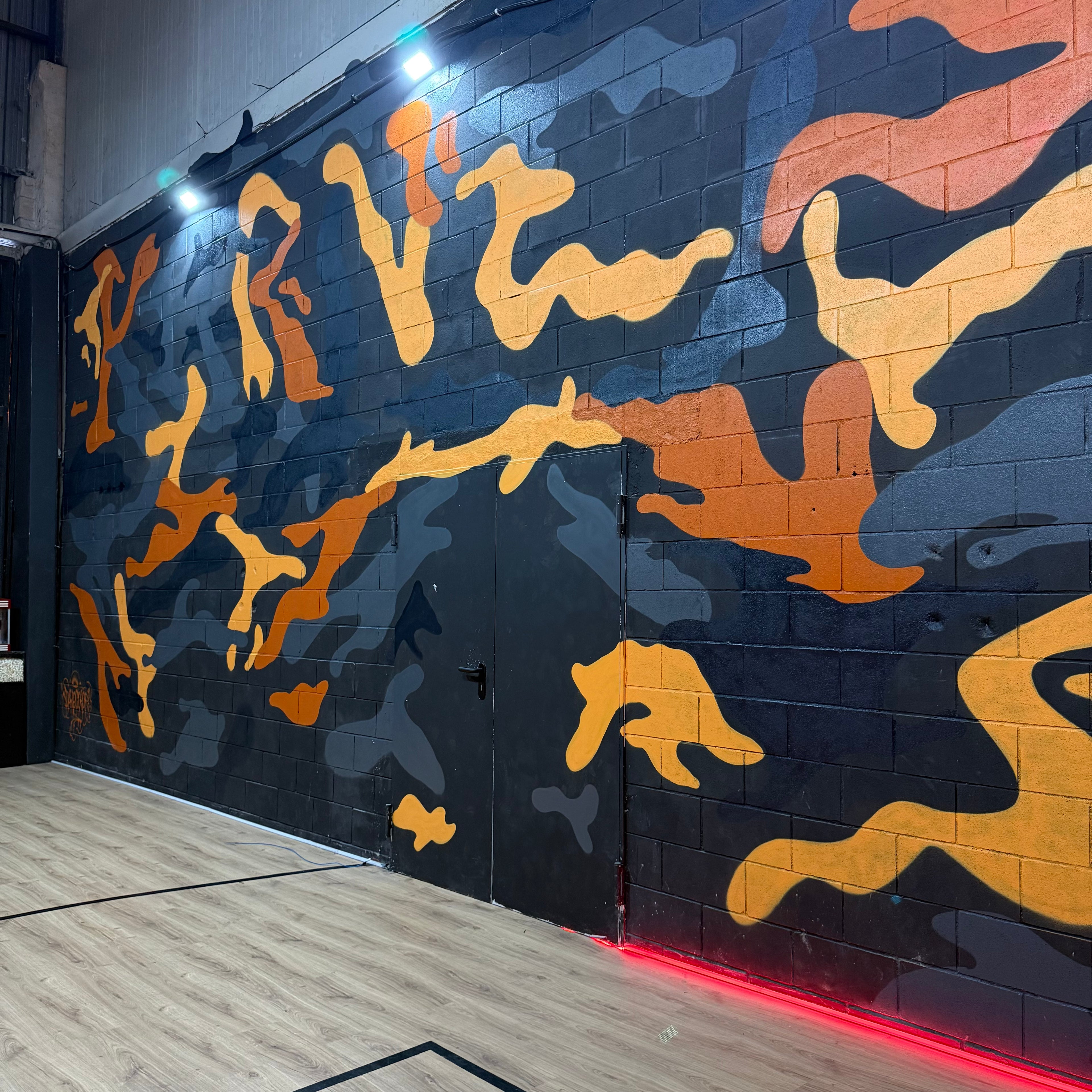 Servicio de murales a domicilio en Madrid. Zona de descanso en estudio de música decorada con graffiti de camuflaje y logotipo corporativo pintado a mano.