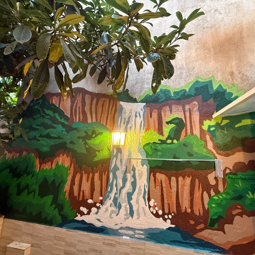 Resultado final de servicio de murales a domicilio en Madrid. Paisaje de naturaleza con cascada integrada al farolillo y árbol real en patio particular.