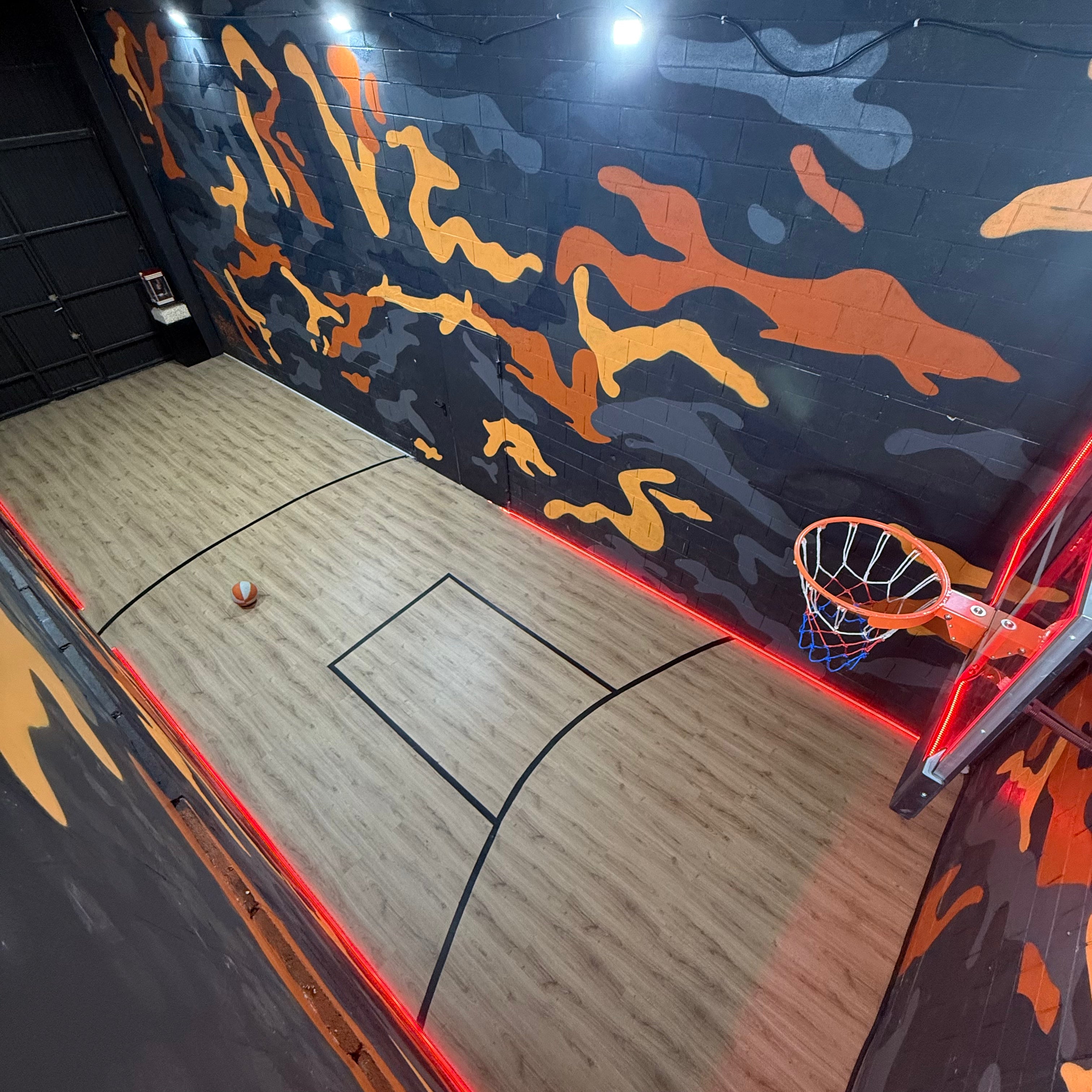 Pintores de graffiti en Madrid decorando el interior de un estudio de música. Cancha de baloncesto con pintura mural de camuflaje naranja y gris.