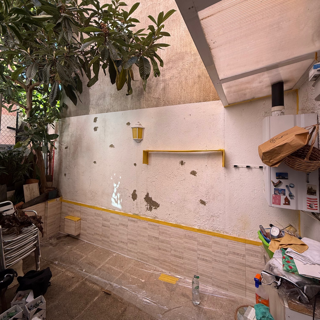 Estado inicial de un patio particular antes de la intervención. Pared deteriorada con farolillo preparada para ser renovada por pintores de murales en Madrid.