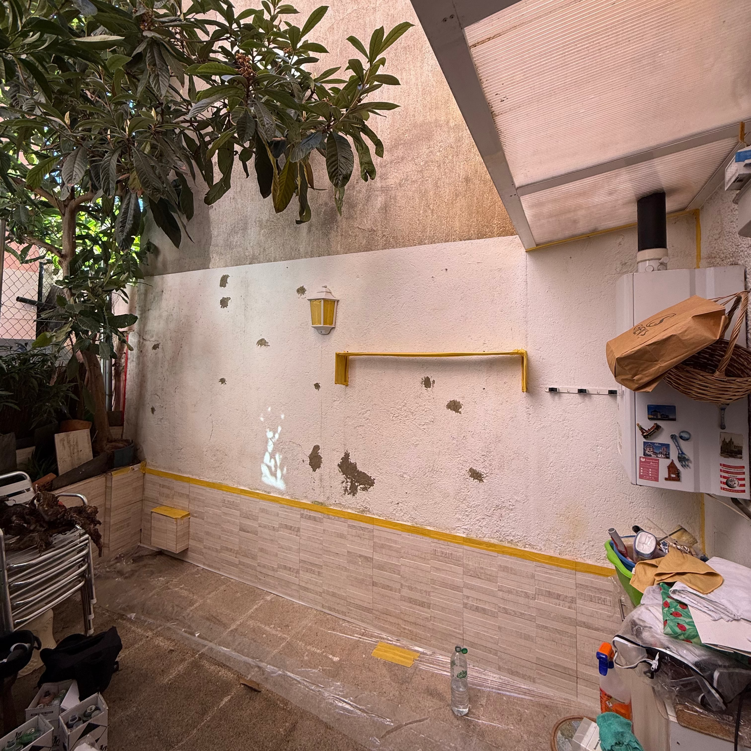 Estado inicial de un patio particular antes de la intervención. Pared deteriorada con farolillo preparada para ser renovada por pintores de murales en Madrid.